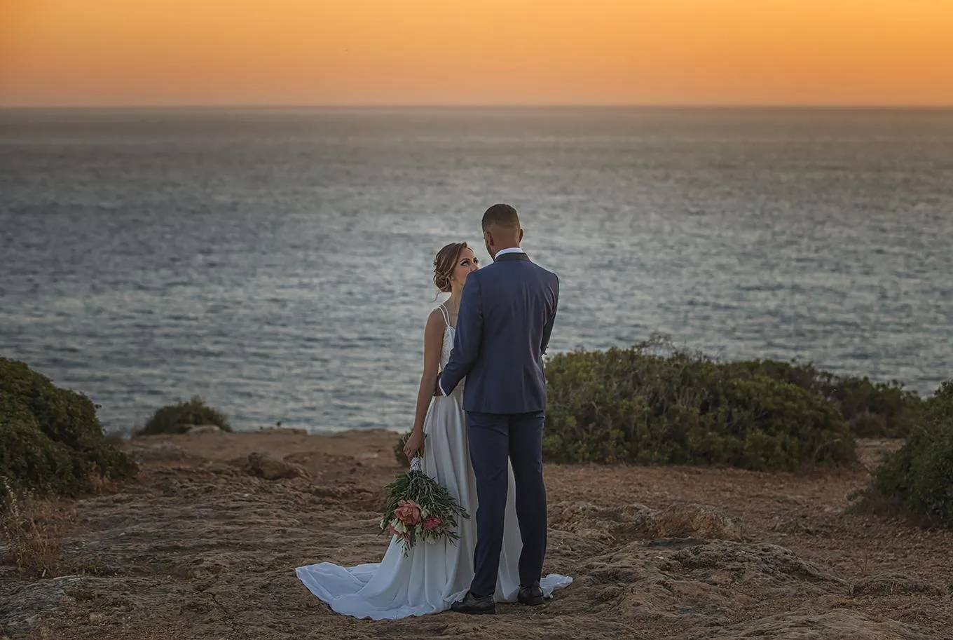 Couple at sunset overlooking the Atlantic on the Algarve coast, the setting for an intimate destination wedding