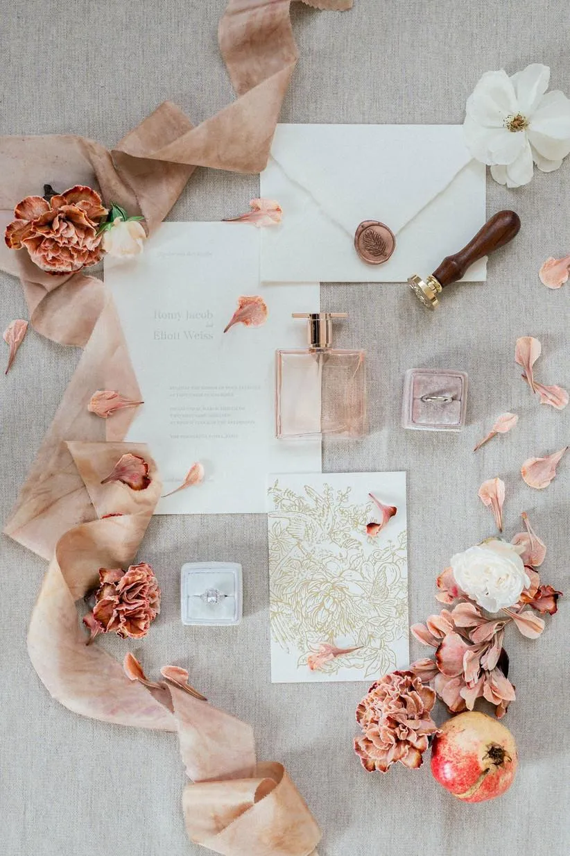 Peach ribbon, wax-sealed invitation suite and dried carnations on linen